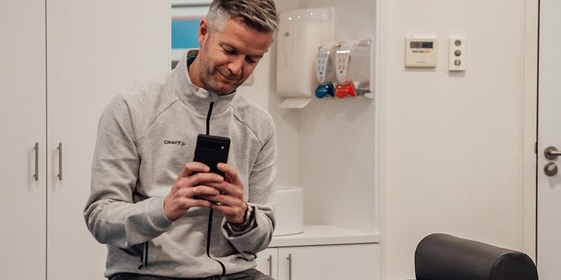 Rembrandt Fysiotherapie & Revalidatie – Smartphone Nekpijn Man werkt met smartphone en voorkomt nekpijn