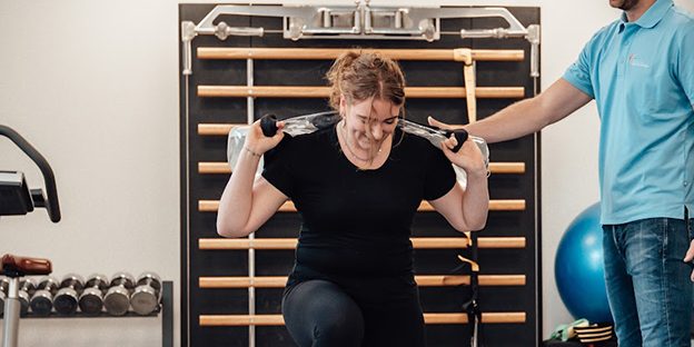 Rembrandt Fysiotherapie & Revalidatie – Rugklachten Suzan heeft last van rugklachten en krijgt ondersteuning van Fysiotherapeut Niels in zijn blauwe shirt