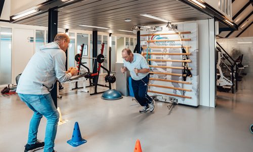 Man doet oefeningen bij therapeut Hans Bloo tijdens sportfysiotherapie in de oefenzaal met een rek