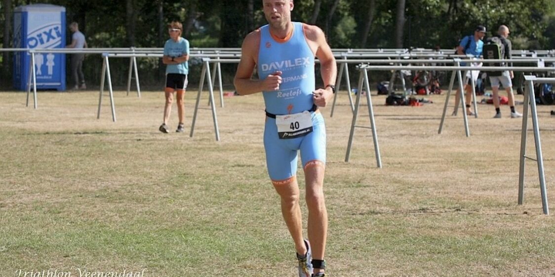 Atleet in een blauw renpak voorkomt een zweepslag aan de kuit en doet mee met een wedstrijd triatlon.