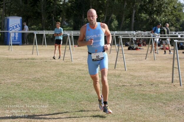 Atleet in een blauw renpak voorkomt een zweepslag aan de kuit en doet mee met een wedstrijd triatlon.