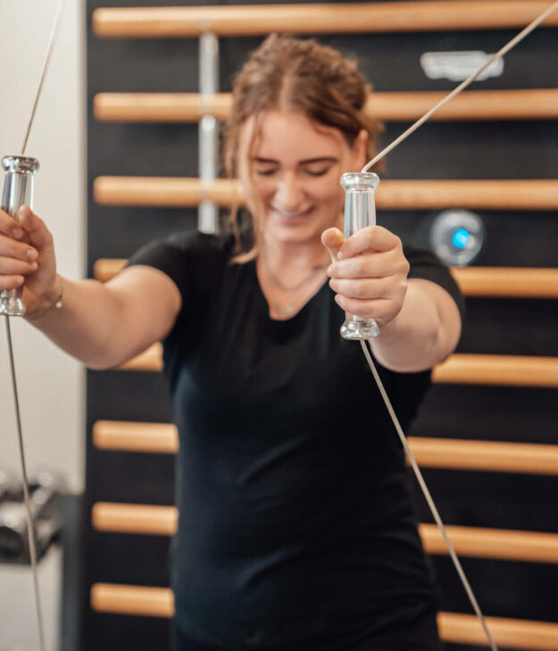 Meisje in een zwart shirt voert oefeningen uit voor haar schouderklachten bij fysiek zwaar werk