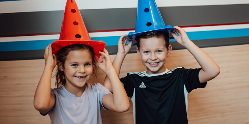 Twee kleine patiënten van kinderfysiotherapie hebben pionnen op hun hoofd.