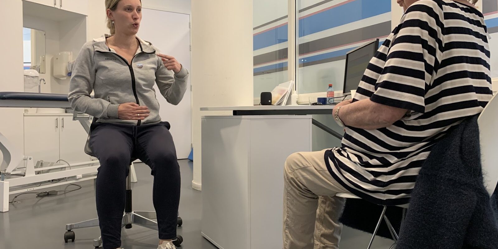 longCOVID – Rembrandt Patiënt in een gestreept shirt met longCOVID wordt geholpen door fysiotherapeut Rianne Doorn in een grijze polo