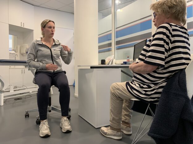 Patiënt in een gestreept shirt met longCOVID wordt geholpen door fysiotherapeut Rianne Doorn in een grijze polo