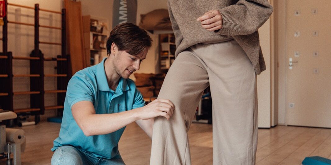 Fysiotherapeut doet oefening met patiënt in zaal
