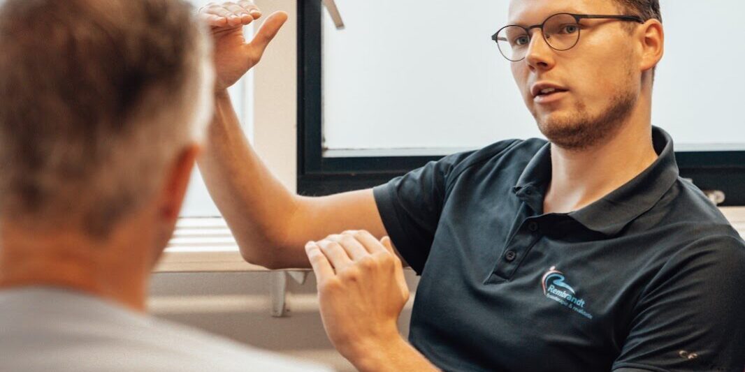 Therapeut geeft uitleg aan een man over ischias