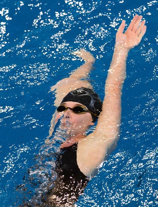 Een dame meteen badmuts en duikbril op haar hoofd in het zwembad de rugslag aan het doen om te profiteren van de voordelen van zwemmen