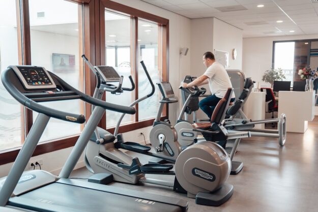 een man op een fitness apparaat om zijn cardio te doen ter voorbereiding van zijn training als krachtige warming-up voor astma