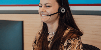 Beweging op kantoor, 5 tips voor een actieve werkdag! vrouw die achter de computer zit met headset op