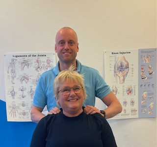 Een fysiotherpeut samen met een patiënt in een behandelkamer